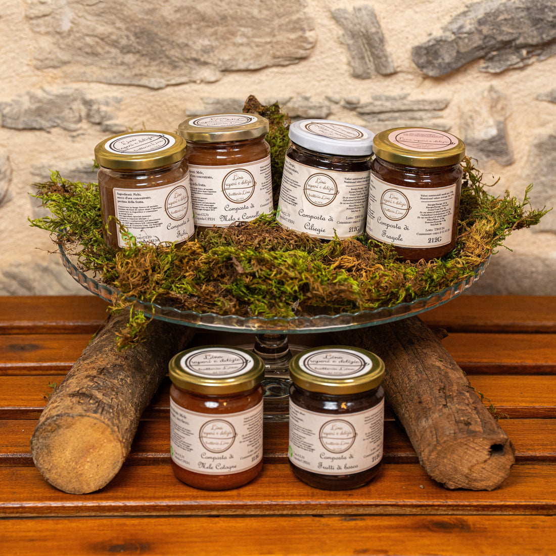 tavolo con 2 vasetti di composta di frutta e dietro un'alzatina con muschio e altri 4 vasetti di composta di frutta